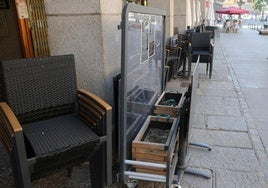 Mobiliario de una terraza, acopiado junto a una fachada en la avenida del Acueducto.