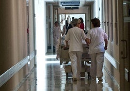 Dos celadoras trasladan una cama en un hospital de la comunidad.