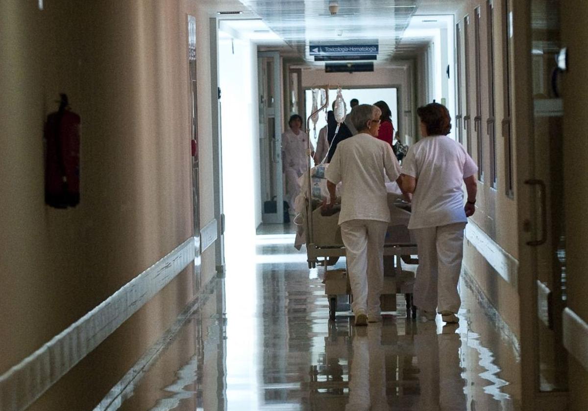 Dos celadoras trasladan una cama en un hospital de la comunidad.