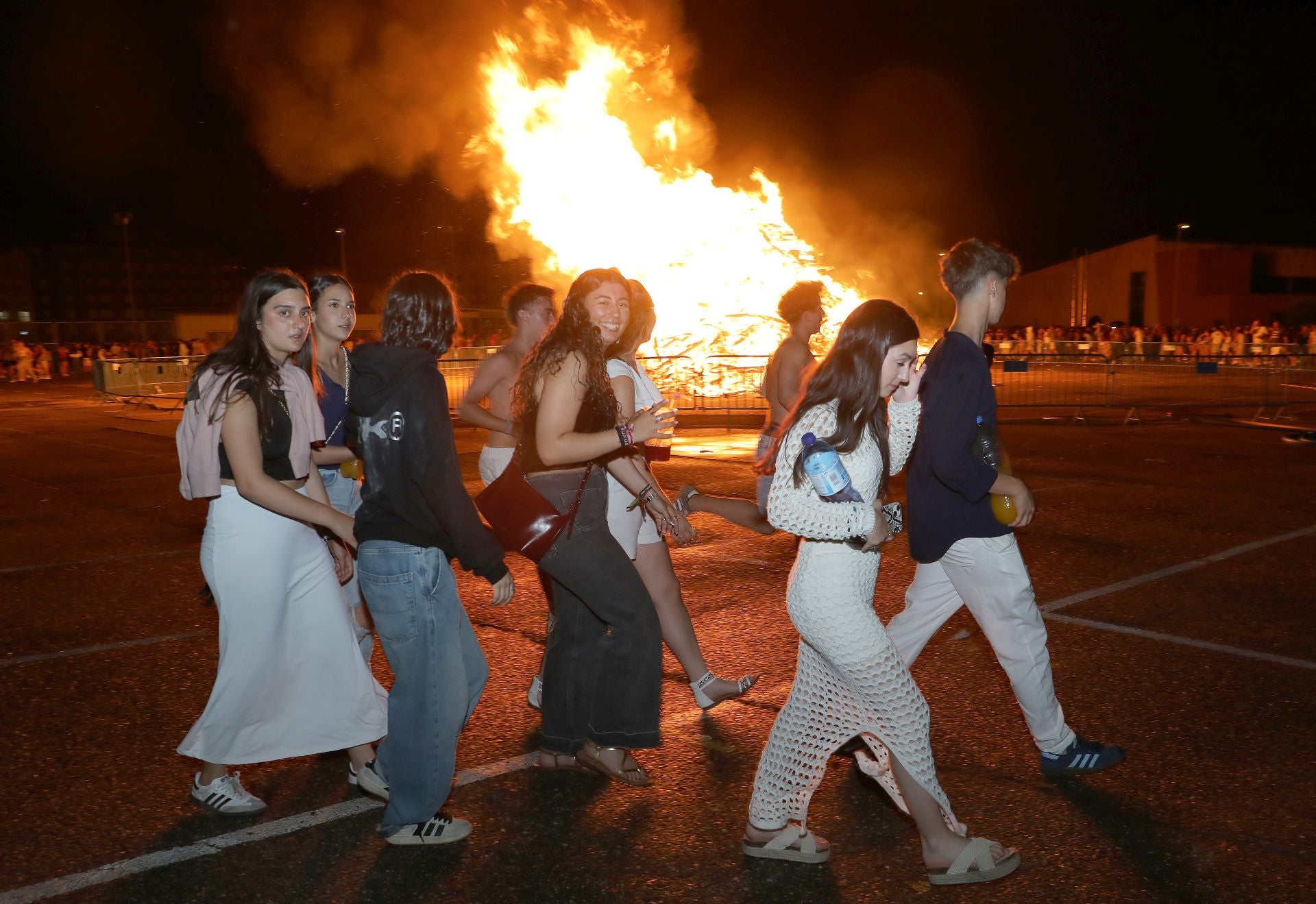 Un grupo de chicos camina alrededor de la hoguera de San Juan.