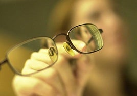 Una mujer muestra las gafas que utiliza.