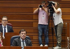 Alfonso Fernández Mañueco sigue las votaciones. Tras él, un fotógrafo y una cámara de RTVCyL.