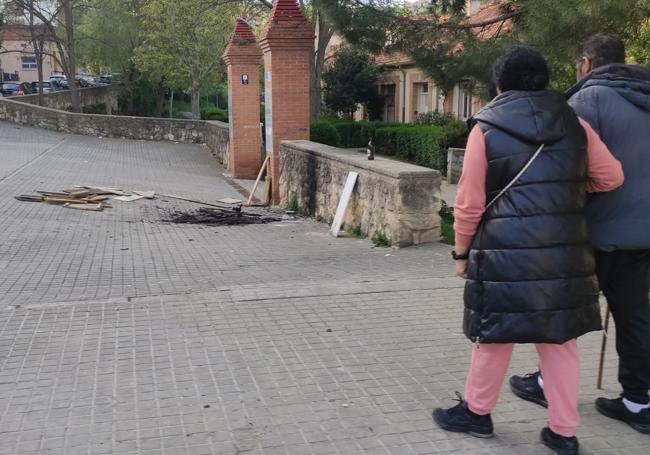 Dos personas pasean junto a los restos de la hoguera realizada el pasado 28 de abril.