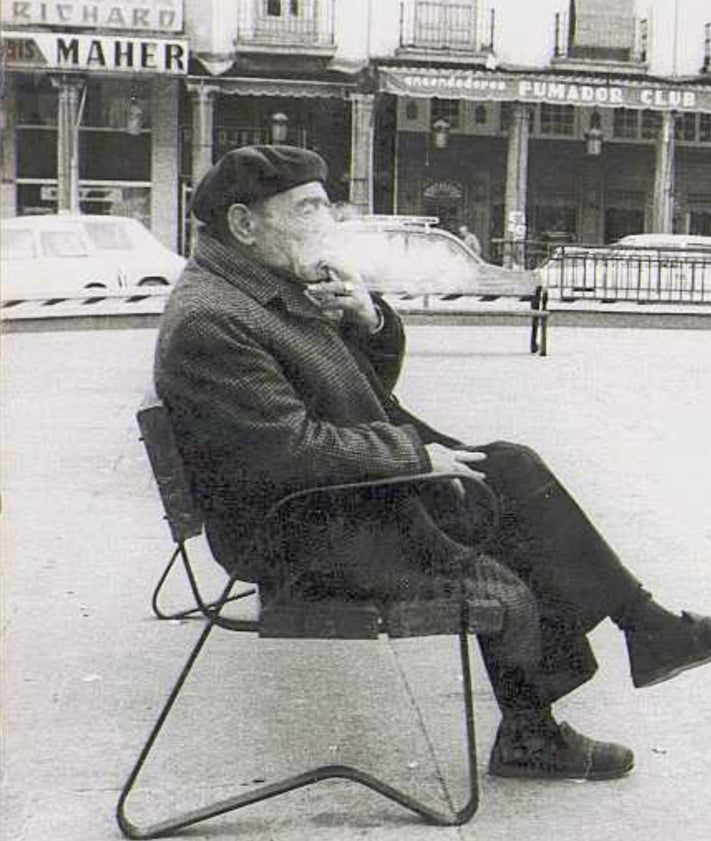 Imagen secundaria 2 - Arriba, Laurentino de la Justicia en el mostrador. Abajo, el carrito de su Centro de Suscripciones frente a la estatua de Colón, y un hombre fumando en la Plaza Mayor, en los años 70, con el Club del Fumador al fondo.