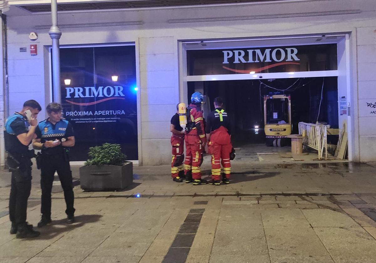 Tres bomberos observan el interior del local tras apagar el pequeño incendio.