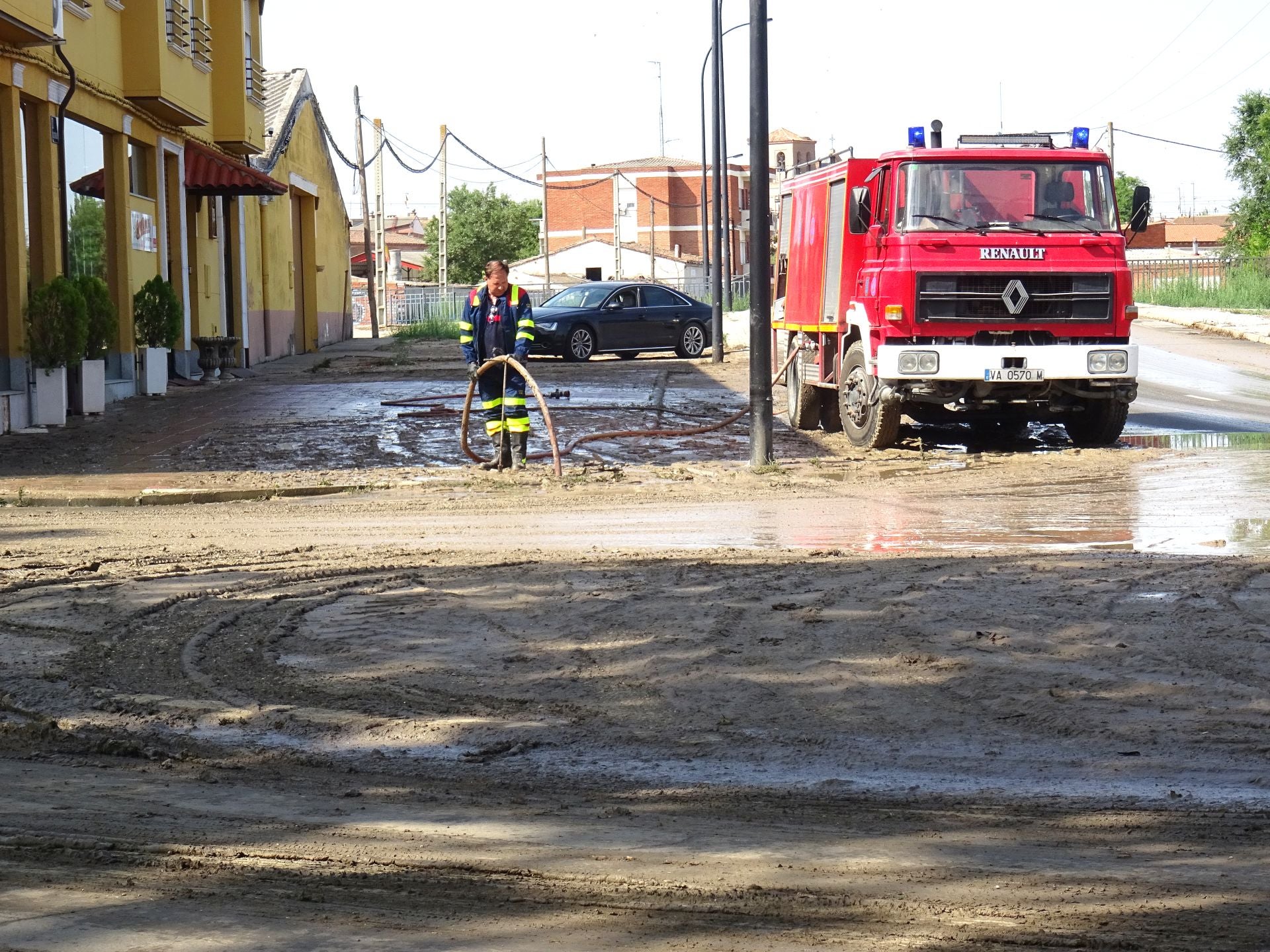 Un bombero limpia la calle tras la tromba que anegó Medina del Campo.