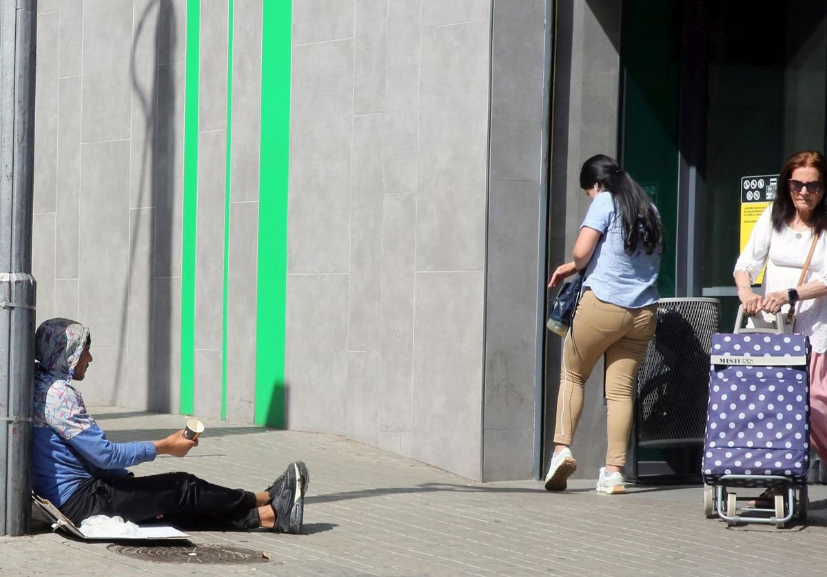 Un hombre pide dinero a las clientas que salen de un supermercado en la capital.