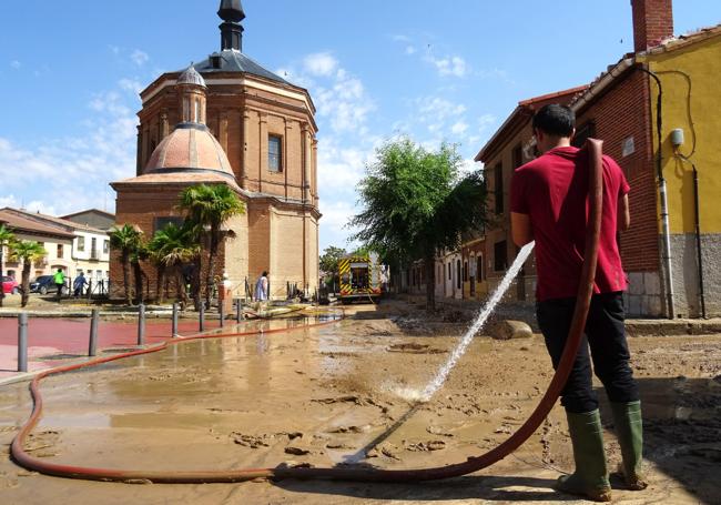 Un vecino limpia el barro acumulado en torno a la ermita del Cristo del Humilladero en Rueda.
