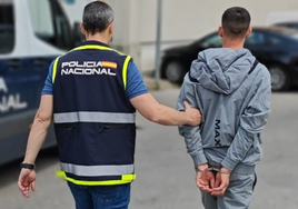 Un agente de la Policía Nacional conduce a comisaría a uno de los detenidos en la operación contra una banda de atracadores.
