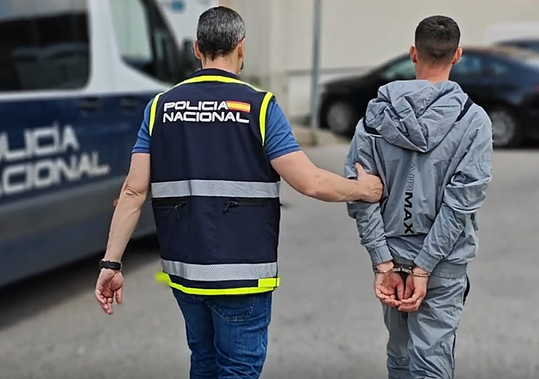 Un agente de la Policía Nacional conduce a comisaría a uno de los detenidos en la operación contra una banda de atracadores.