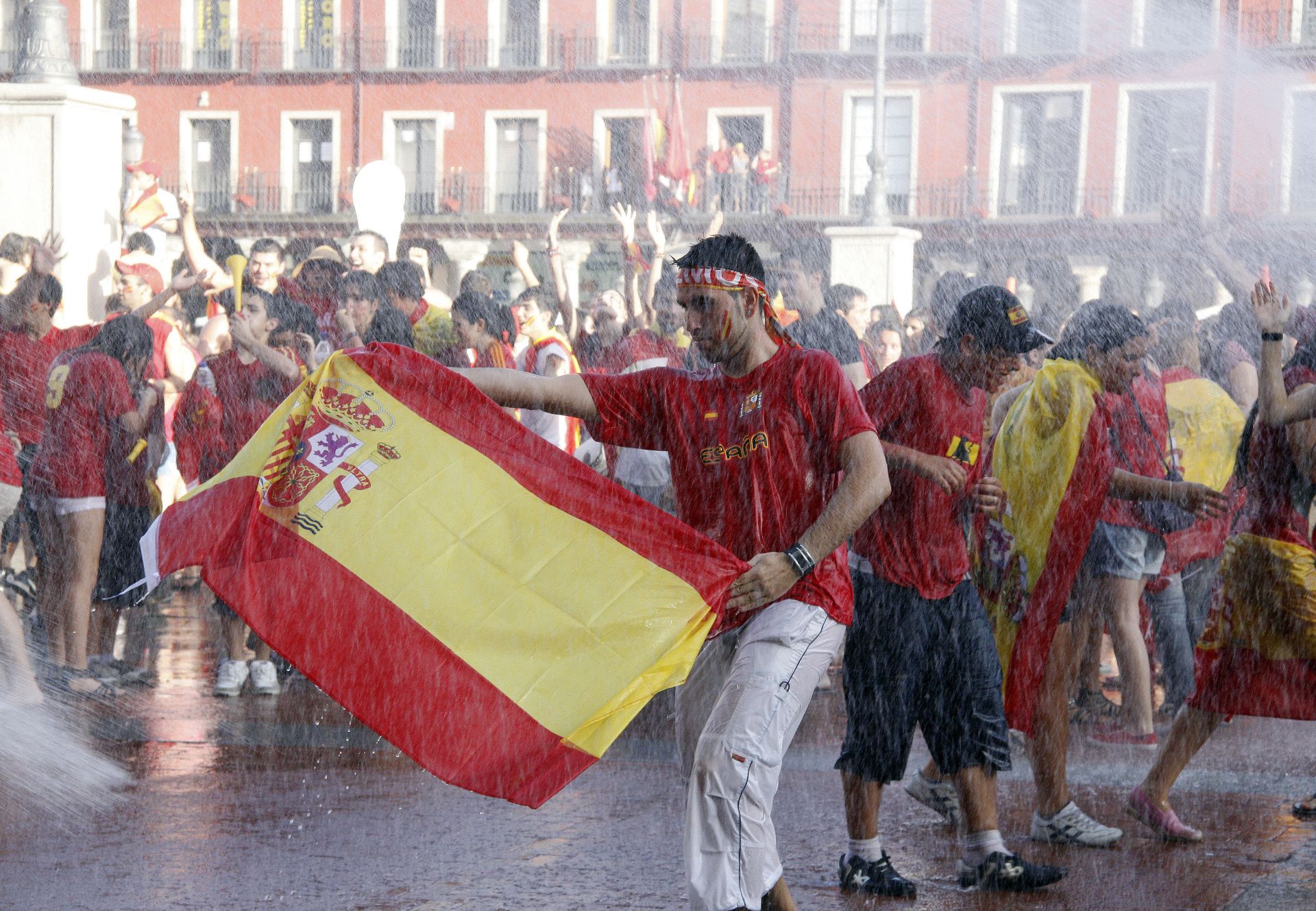 Los aficionados festejan en la Plaza Mayor de Valladolid mientras los bomberos les lanzan agua para refrescarlos.