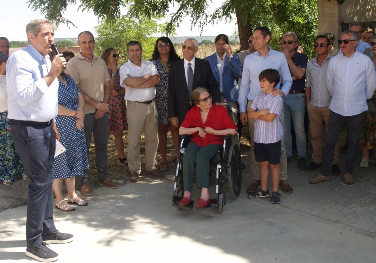 Los maestros María Josefa Díaz, en silla de ruedas, y su esposo Manuel Perucho, de pie a su lado, escuchan las palabras del alcalde de Íscar durante la inauguración de su calle.