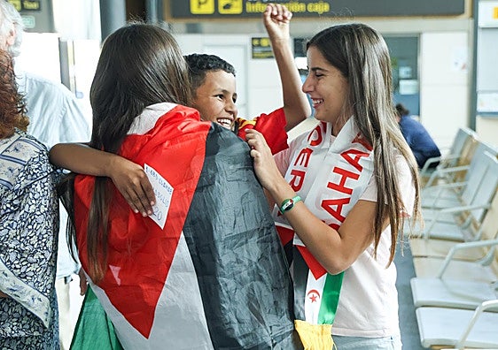 Dos jóvenes de la familia de acogida reciben a un niño saharaui.