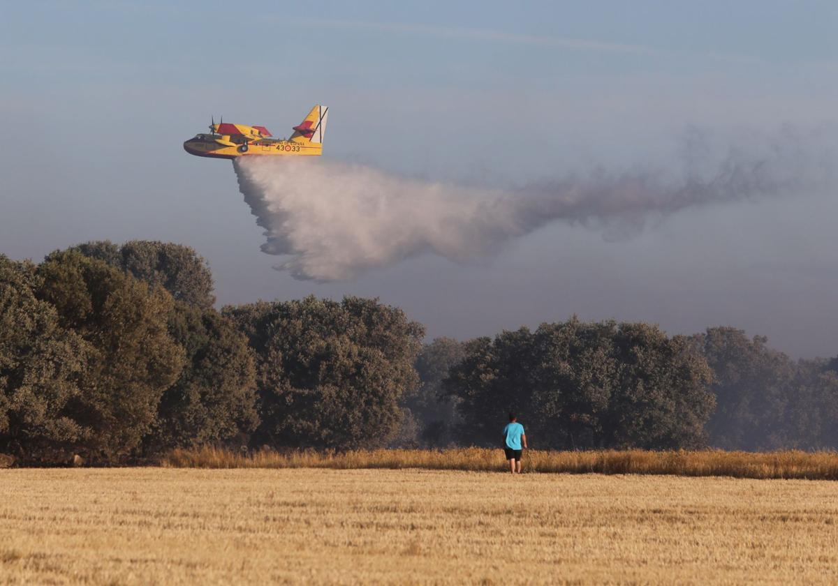 Una avioneta de la Junta esparce agua en la zona en llamas, en lo alto del valle de San Juan, junto al Monte.