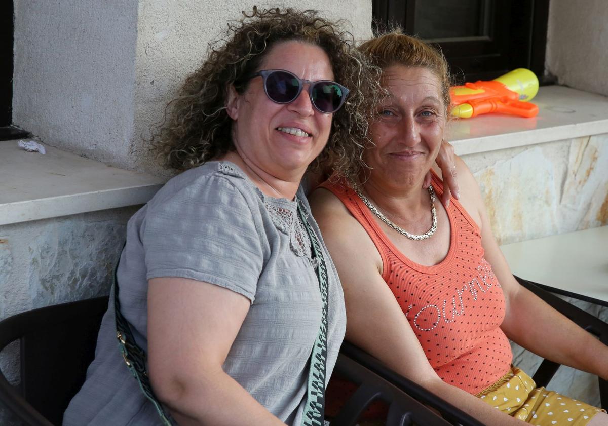 Imagen principal - Arriba, dos mujeres, una española y otra extranjera, se abrazane n la terraza de un bar. Abajo algunos vecinos magrebíes charlan a las afueras del local, y a la izquierda, dos vecinos comparten una cerveza después del trabajo.