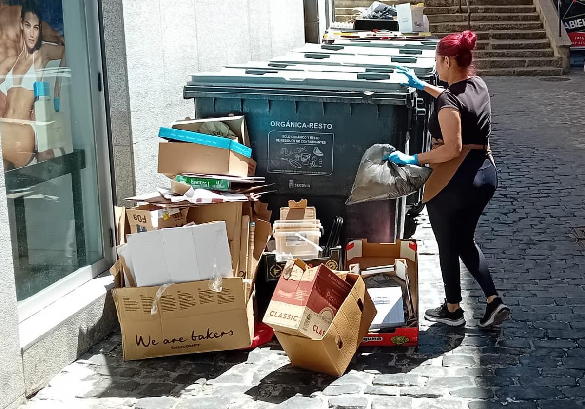 La trabajadora de un céntrico comercio de Segovia arroja residuos a un contenedor.