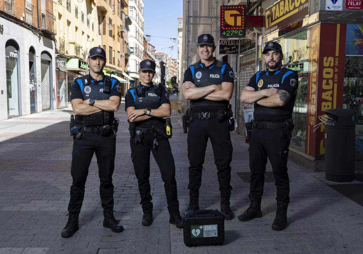 Los agentes de la Policía Municipal de Valladolid Javier, Laura, José María de Diego y Luis (tres de ellos prefieren no facilitar su apellido) posan junto a un desfibrilador frente al lugar de la calle Mantería donde salvaron la vida a una mujer en parada cardiorrespiratoria.
