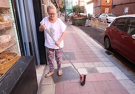 Milagros Salgado barre la acera con gravilla a la puerta de su panadería de la calle Linares.