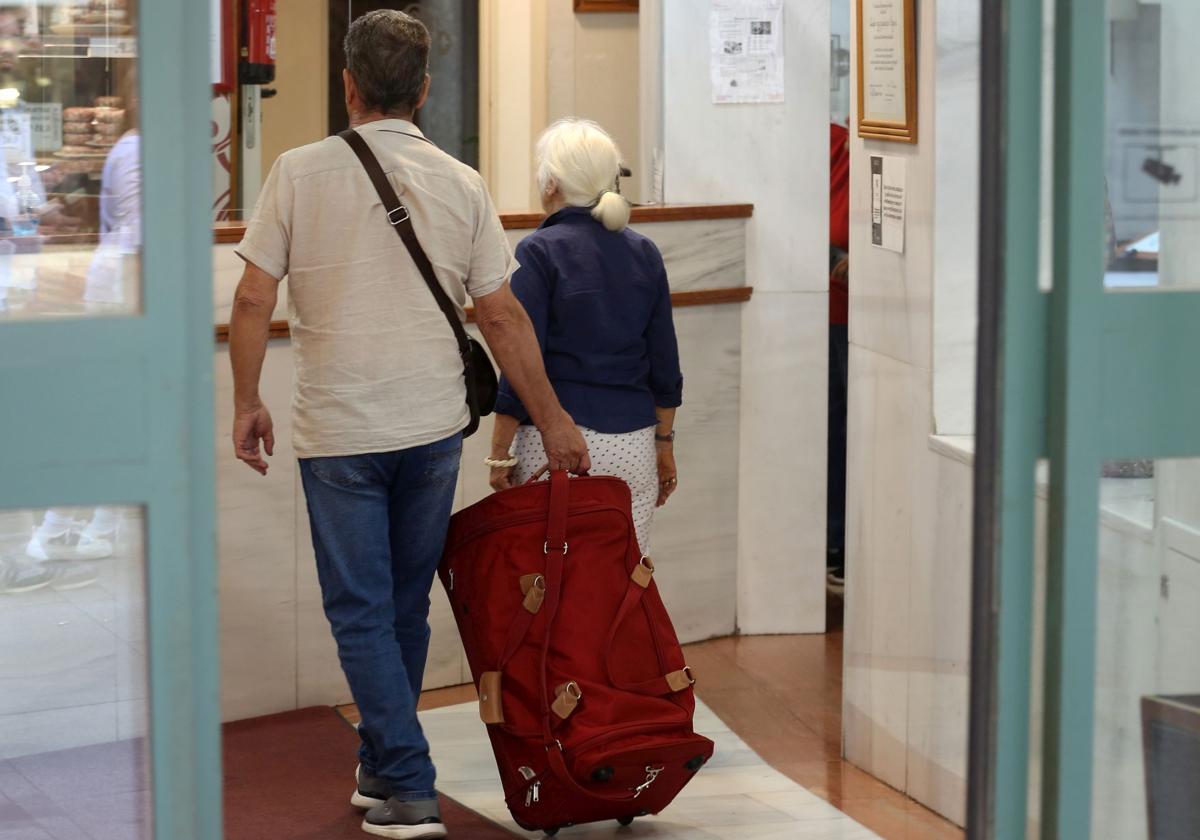 Dos turistas se dirigen con su equipaje a la recepción de un céntrico hotel de Segovia.