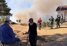 Vecinos y agentes siguen de cerca la evolución del incendio, este martes por la mañana.