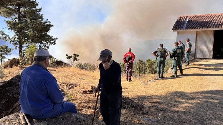 Vecinos y agentes siguen de cerca la evolución del incendio, este martes por la mañana.