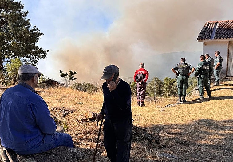 Vecinos y agentes siguen de cerca la evolución del incendio, este martes por la mañana.