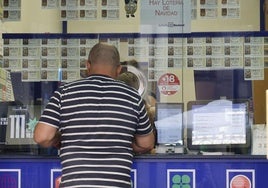 Un hombre adquiere un décimo en un despacho de loterías.