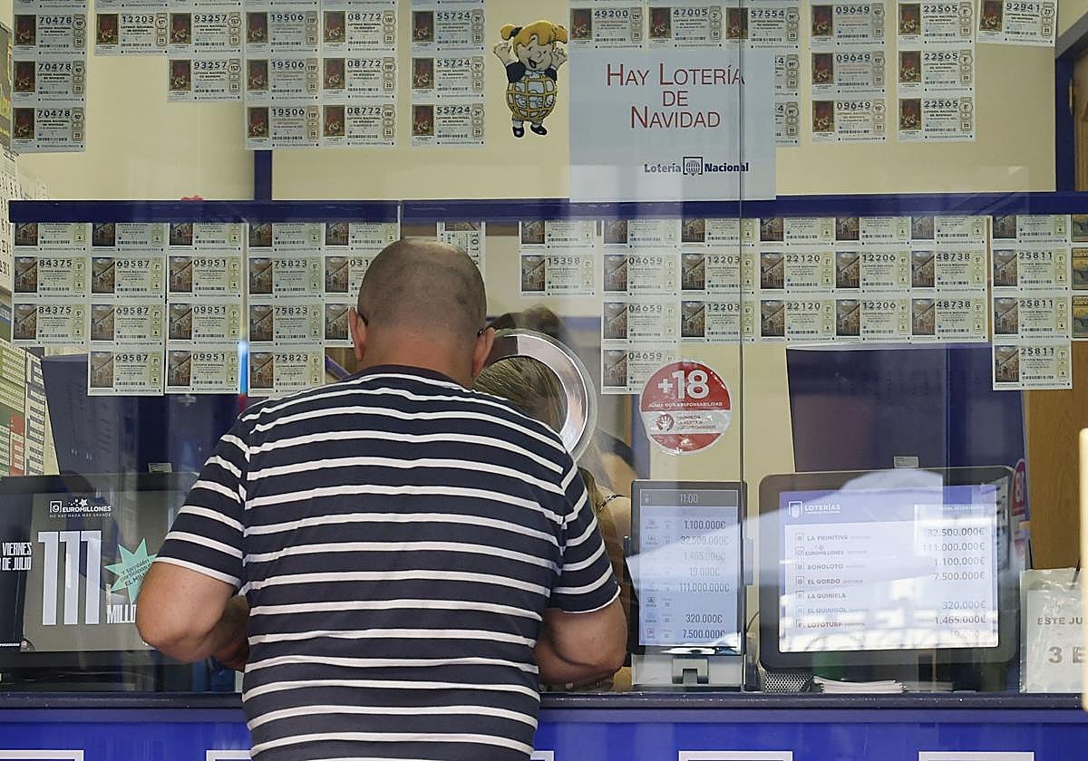 Un hombre adquiere un décimo en un despacho de loterías.