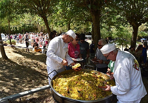 Los cocineros sirven raciones de paella a los asistentes, que forman una larga cola.