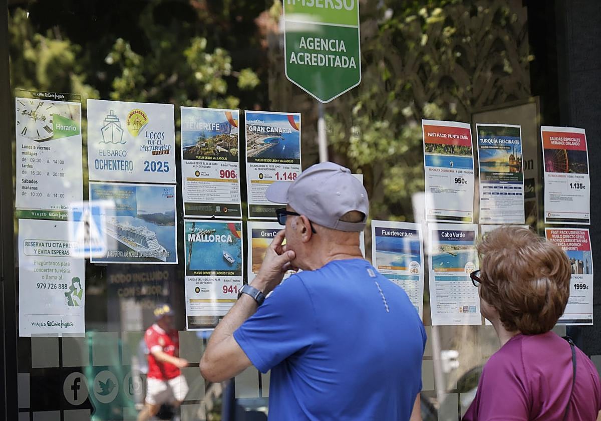 Dos personas consultan los viajes anunciados en la agencia de El Corte Inglés de Palencia.