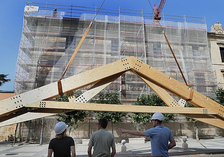 Los operarios observan cómo la grúa sube una de las vigas al tejado de Palacio Episcopal, este lunes.