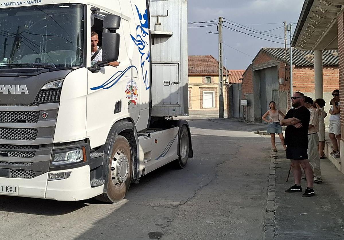 Un camión pasa junto a varios vecinos delante de una vivienda de Chañe.
