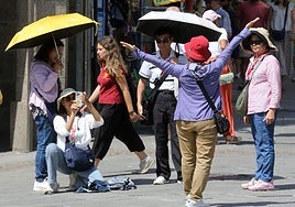 Turistas se protegen del sol con gorros y paraguas en Segovia.
