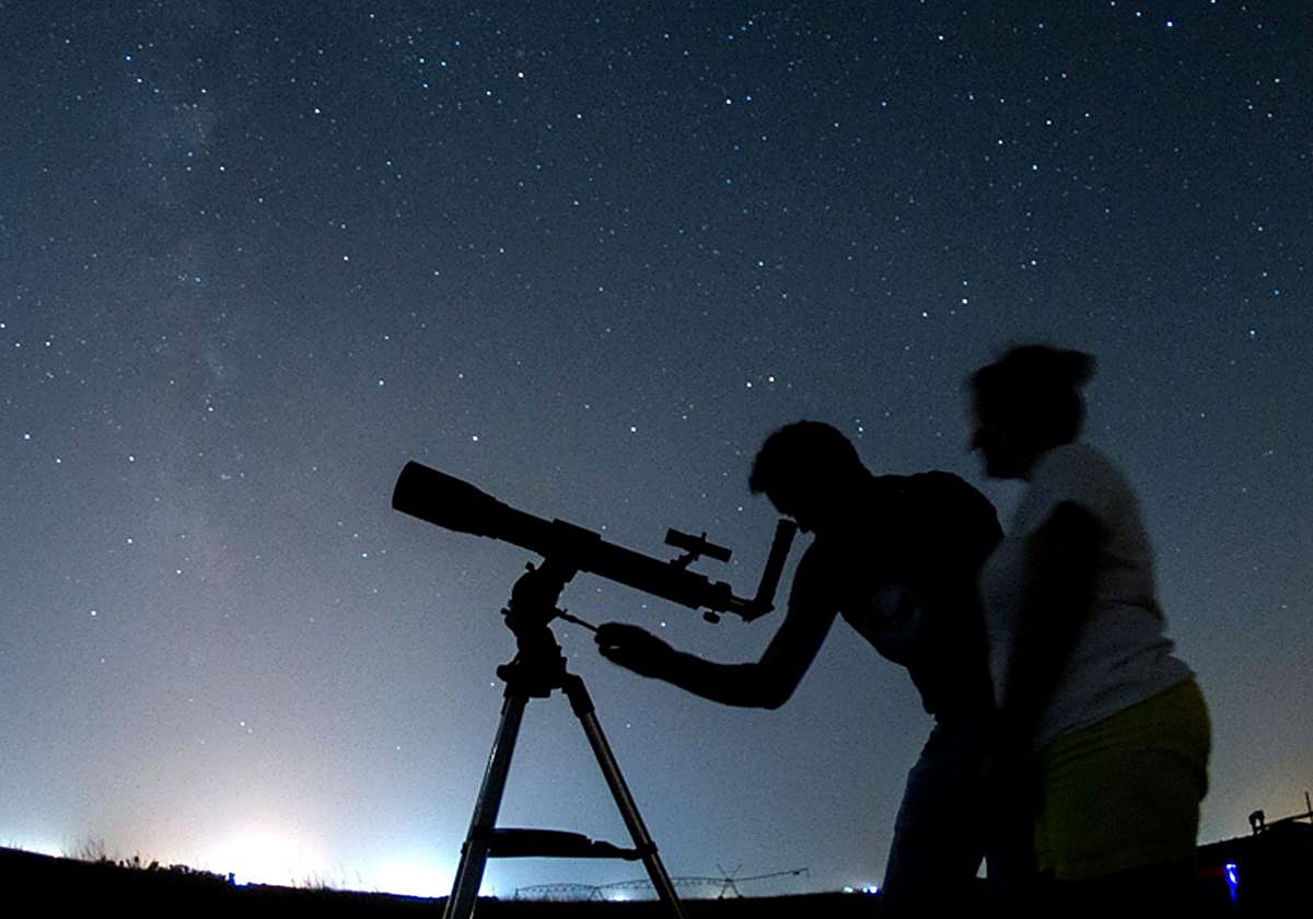 Dos personas observan las estrellas con un telescopio.
