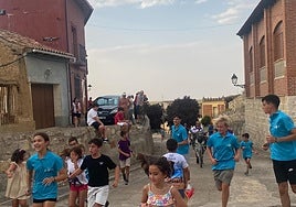 Niños y jóvenes corren delante del carretón en una recreación lúdica de la vaca enmaromada