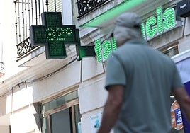 Un hombre camina por delante de una farmacia durante una jornada de esta ola de calor.