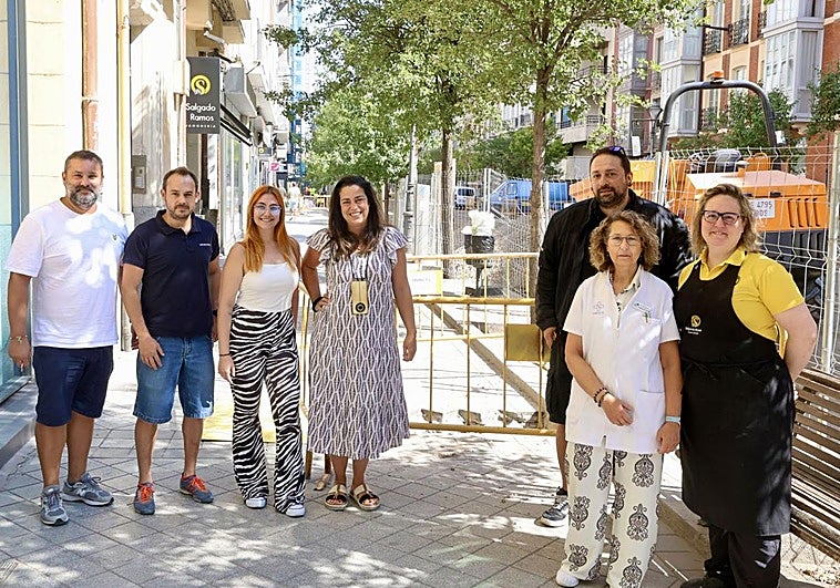 Propietarios y empleados de varios negocios de Gamazo posan junto a las vallas de la obra.