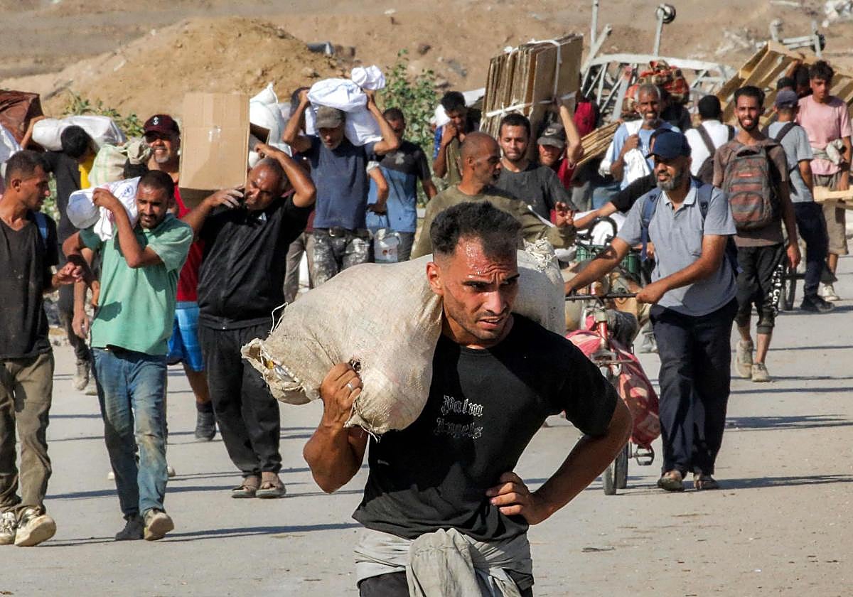 Habitantes de Gaza cargan con sacos de ayuda humanitaria.