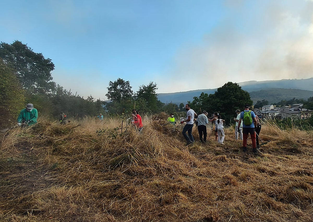 Imagen secundaria 1 - El fuego y el humo desde San Ciprián y vecinos del pueblo haciendo labores de desbroce.