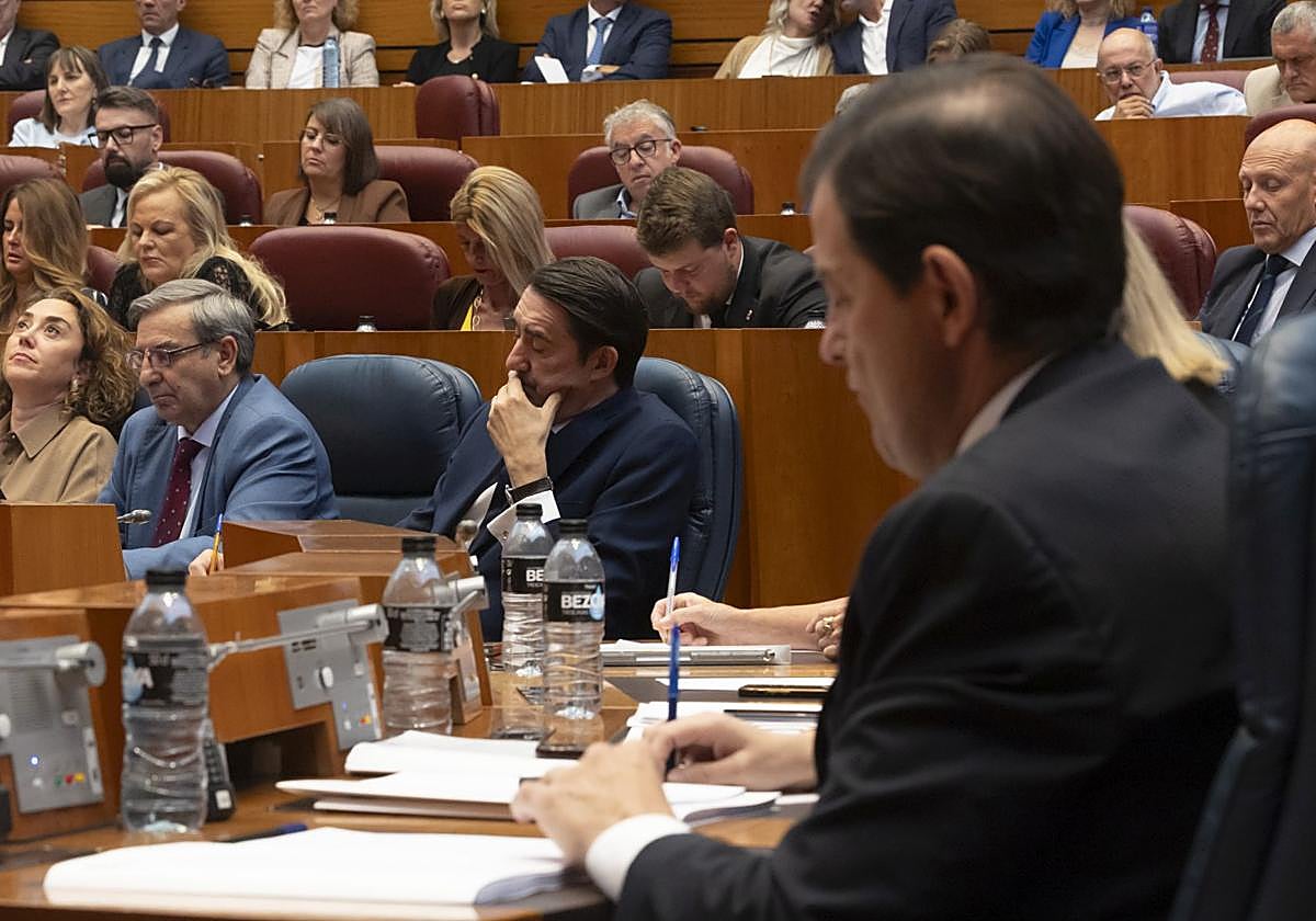 Fernández Mañueco toma notas en su escaño en el pleno de los incendios. El consejero Suárez-Quiñones, al fondo.