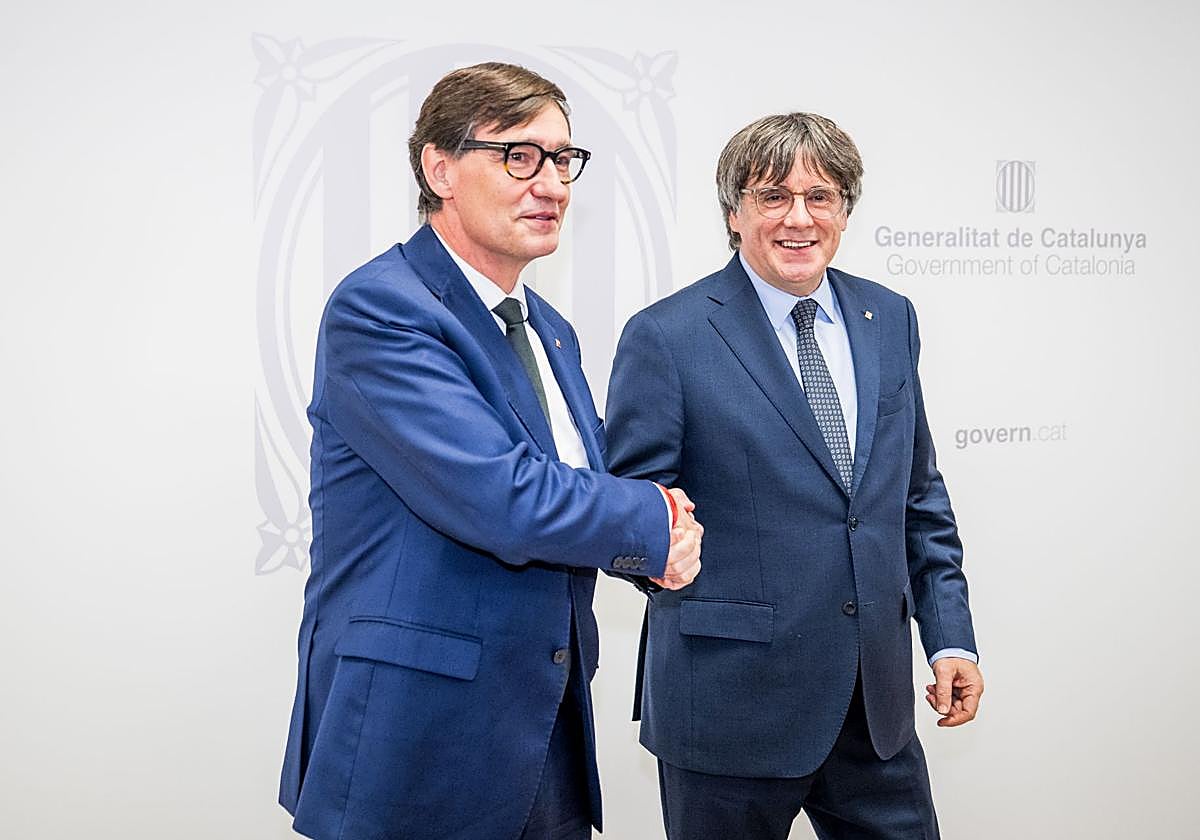 El presidente de la Generalitat, Salvador Illa (i), saluda al presidente de Junts per Catalunya, Carles Puigdemont (d), durante una reunión, el 2 de agosto de 2025, en Bruselas.