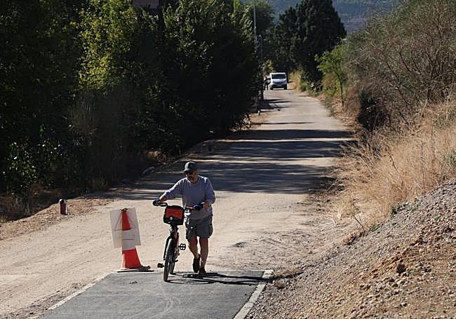 Un ciclista se baja de la bici para salvar el desnivel en el único tramo de carril bici que alcanza el camino de Hornillos.