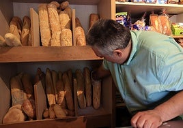 Un trabajador en un obrador situado en la ciudad coge una barra de pan del estante.