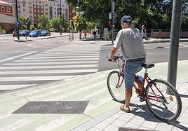 Un ciclista se dispone a cruzar el paso de peatones del puente de Isabel la Católica.