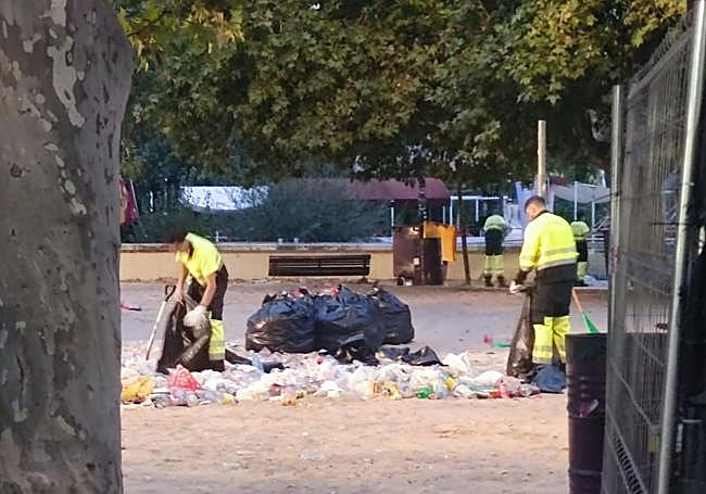 Dos operarios recogen la basura amontonada en Las Moreras en la noche del domingo.