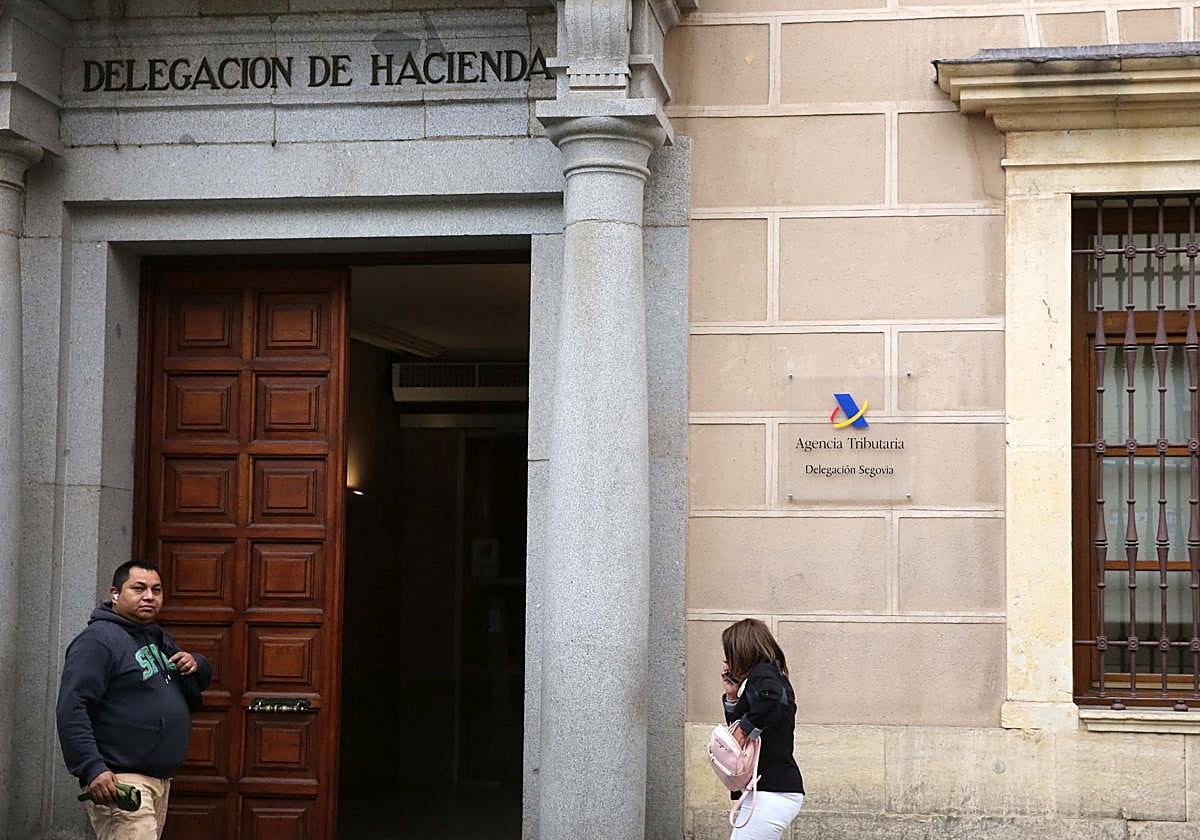 Dos personas caminan junto al acceso a la delegación de Hacienda en Segovia.