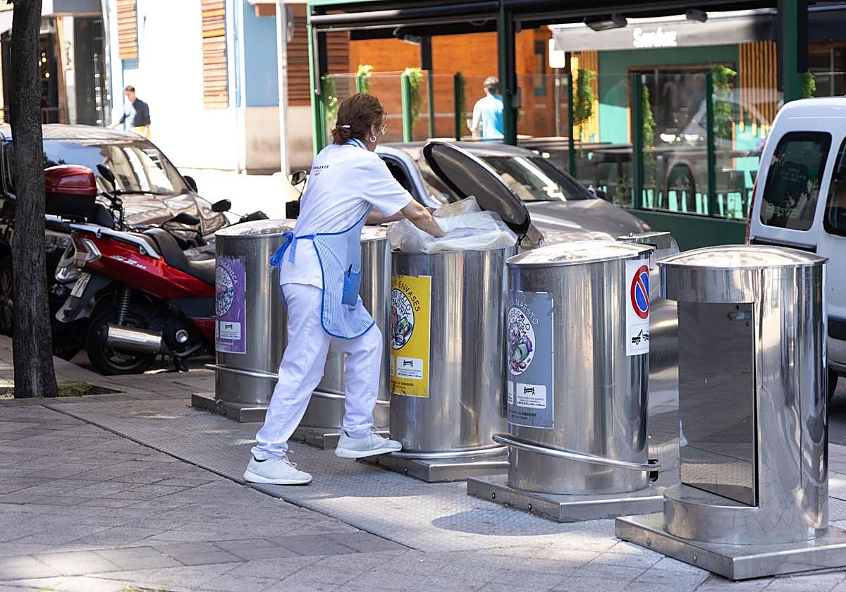 Una mujer tira basura en un contenedor de Valladolid, en una imagen de archivo.