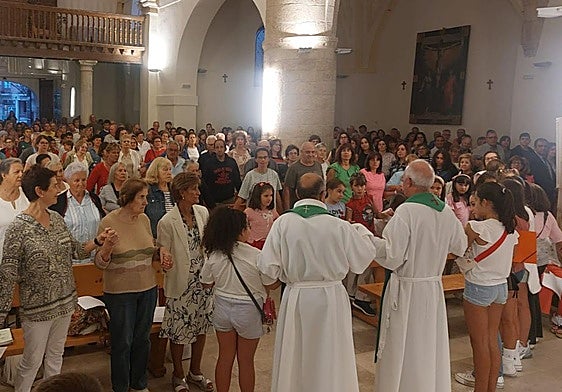 Los vecinos forman una cadena para darse la paz en la misa del viernes por la tarde en Saldaña.