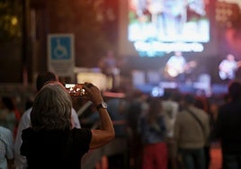 Una mujer graba con su móvil una actuación musical en Las Moreras, lugar de uno de los hurtos.