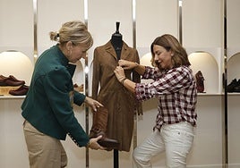 Ana Villacorta y Puri Peral prueban el conjunto de una chaqueta larga en el maniquí con las botas.